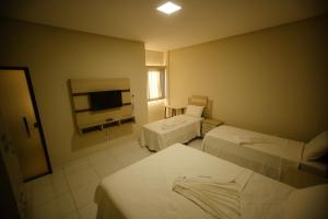 a hotel room with two beds and a flat screen tv at O Neves Hotel in Guanambi