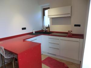 a kitchen with white cabinets and a red counter top at B&B Le Peschiere in Montefiorino