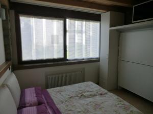 a small bedroom with a bed and two windows at B&B Le Peschiere in Montefiorino