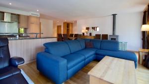 uma sala de estar com um sofá azul e uma cozinha em Chalet Fortuna 2 em Wengen