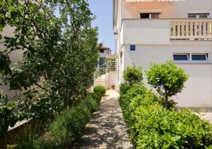 un camino que conduce a un edificio con arbustos en Apartments Mima, en Zadar
