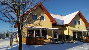 a house with snow on the ground at Pokoje Gościnne Przylesie in Łobez