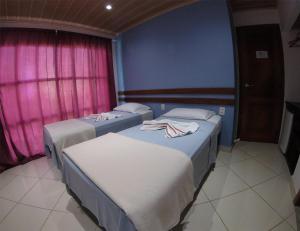 two beds in a room with pink and blue walls at Pousada Belafonte Riocentro in Rio de Janeiro