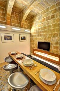 a dining room with a table and chairs and a stone wall at Coral Apartment (Valletta) in Valletta +15 photos