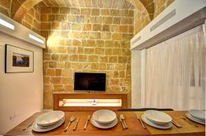 ein Esszimmer mit einem Tisch mit Tellern und einem TV in der Unterkunft Coral Apartment (Valletta) in Valletta