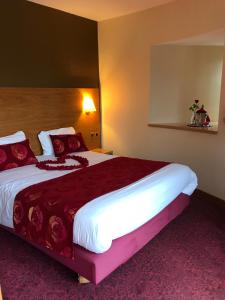 a hotel room with a large bed with red pillows at Hôtel Tour Maje in Rodez