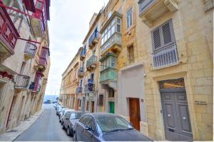a row of cars parked on a street with buildings at Coral Apartment (Valletta) in Valletta