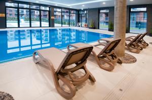 a swimming pool with chairs and a table in a building at AquaBaltic in Kołobrzeg