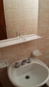 un lavabo de baño con un cristal sobre un estante en Hotel Bamba en Villa Gesell