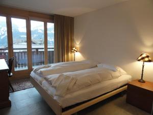 um quarto com uma cama e uma grande janela em Chalet Bella Vista 6 em Wengen