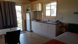 - une cuisine avec des placards blancs, un évier et une table dans l'établissement Harbour Lights Tourist Park, à Bowen