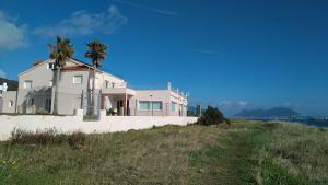 a white house on a hill with palm trees at Punta Carnero Hostal in Algeciras