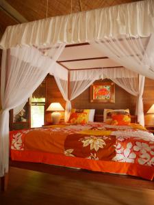 a bedroom with a canopy bed with white curtains at Fare Ahuna in Bora Bora