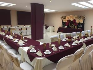 une salle de conférence avec une grande table et des chaises blanches dans l'établissement Novotel, à Poza Rica de Hidalgo