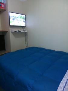 een slaapkamer met een blauw bed en een flatscreen-tv bij Departamento Volcán Corcovado in Puerto Montt