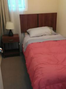 1 dormitorio con 1 cama con manta roja y lámpara en Departamento Volcán Corcovado, en Puerto Montt