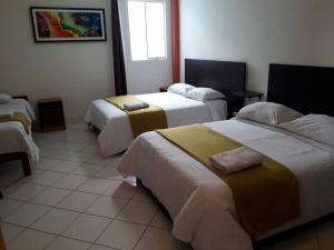 um quarto de hotel com duas camas e uma janela em Le Saint-Etienne em Trujillo