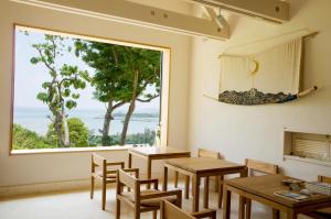 a room with tables and chairs and a large window at Kaiza in Nanjo