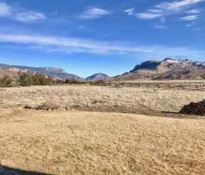 un campo de hierba seca con montañas al fondo en Yellowstone Cutthroat Guest Ranch, en Wapiti