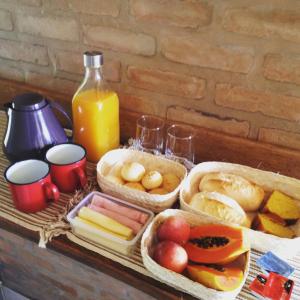 a table with three baskets of food and a bottle of orange juice at Lavras Real in Lavras Novas