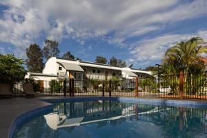 a swimming pool in front of a house with a fence at Novena Palms Motel in Brisbane