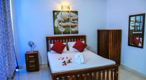 1 dormitorio con 1 cama con almohadas rojas en Christima Residence en Negombo