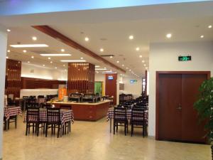 Motel Xiamen Railway Station في شيامن: مطعم بطاولات وكراسي في مبنى