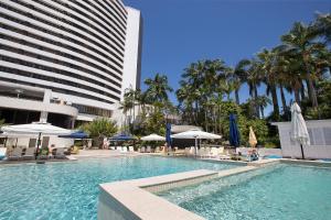 uma piscina com cadeiras e guarda-sóis ao lado de um edifício em The Star Grand at The Star Gold Coast em Gold Coast