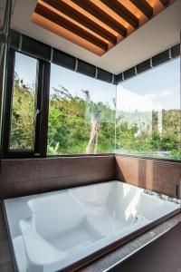 a bath tub in a room with a large window at Dreamer Boutique Hotel in Nanwan