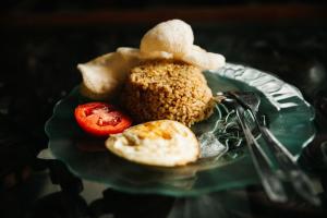 a plate of food with eggs and a tomato at La Javanaise Home Stay Malioboro in Yogyakarta