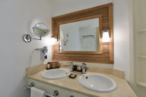 a bathroom with two sinks and a large mirror at Canonnier Beachcomber Golf Resort & Spa in Pointe aux Canonniers