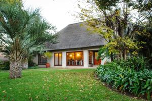 a house with palm trees in front of a yard at Safari Club Guest Lodge OR Tambo International Airport in Kempton Park