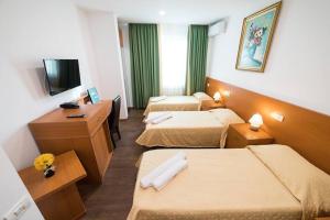 um quarto de hotel com três camas e uma televisão em London Hotel em Constança