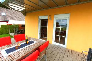 a deck with red chairs and a table with a bottle of wine at Haus STRANDLAeUFER _ EG_Fewo in Göhren-Lebbin