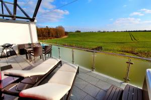 un balcone con sedie, tavolo e campo verde di Villa Grande Fewo Relax We 4 a Göhren-Lebbin