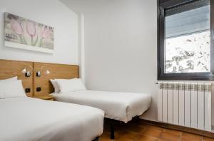 2 Betten in einem Zimmer mit Fenster in der Unterkunft Apartamentos Prat de les Molleres in Soldeu