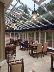 a conservatory with tables and chairs and windows at Steeton Hall Hotel & Restaurant in Steeton