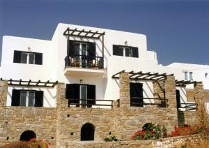 a white building with black windows and a stone wall at San Antonio Summer House in Piso Livadi