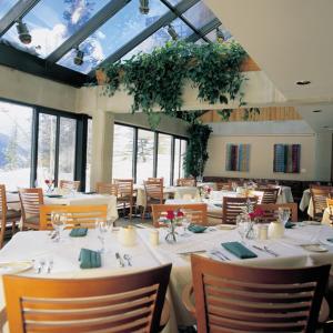 a dining room with white tables and chairs and windows at The Lodge at Snowbird in Alta