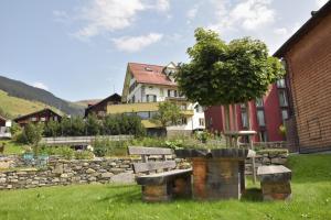 ein Park mit einer Bank, einem Baum und einem Gebäude in der Unterkunft Hotel Vallatscha in Curaglia