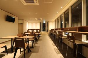 a restaurant with tables and chairs and windows at Cabin & Capsule Hotel J-SHIP Osaka Namba in Osaka