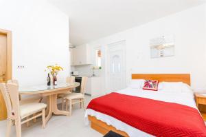 um quarto com uma cama vermelha e uma mesa em Apartments Rose em Sućuraj