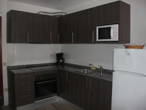 a kitchen with wooden cabinets and a white refrigerator at VicAm Atico Duplex in Pineda de Mar