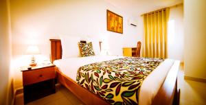 Una habitación de hotel con una cama grande y una lámpara. en Hotel Adagio, en Libreville
