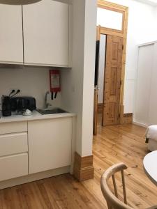 cocina con armarios blancos y suelo de madera en Casa da Praça Square Suites, en Coímbra