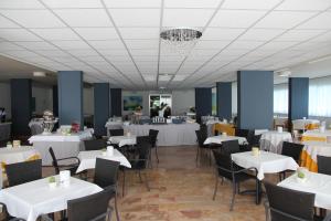 un comedor con mesas y sillas blancas en Hotel Smeraldo, en Abano Terme