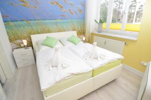 a bedroom with a bed with white sheets and a window at Villa Sirene - Wohnung 08 in Binz