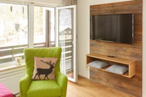 a green chair with a deer pillow in a living room at Ferienwohnung Kraus in Tiefenbach bei Oberstdorf