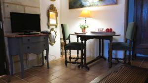 Zimmer mit einem Schreibtisch, einem TV und einem Tisch mit Stühlen. in der Unterkunft La cave de l'éperon in Trôo