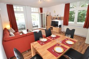 奧茨巴德賓茲的住宿－Villa Strandidyll Wohnung 9，客厅配有桌子和红色沙发
